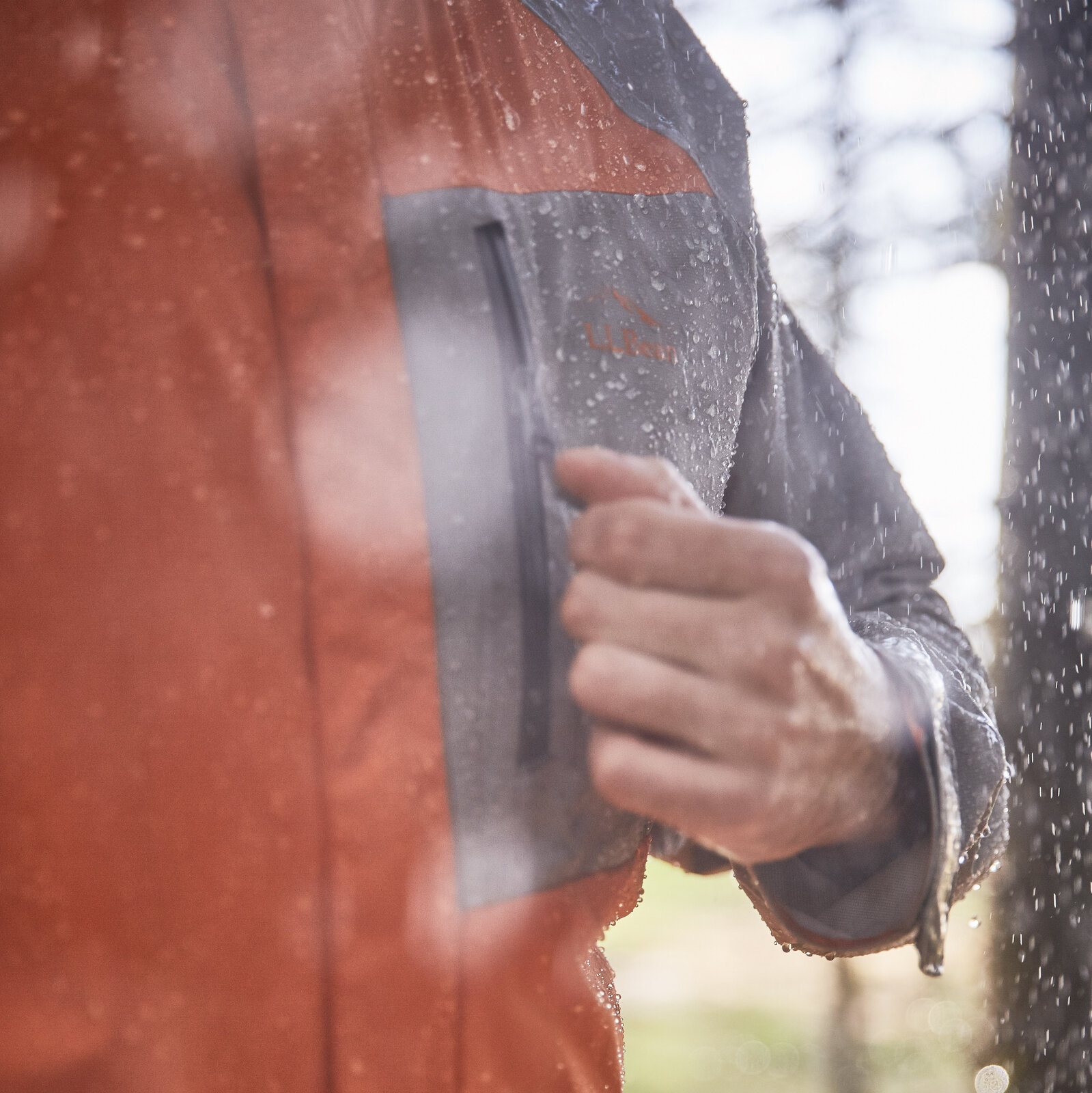 L.L.Bean logo on blue jacket chest, rain droplets on fabric.